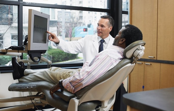 врач показывает сидящему пациенту что-то на мониторе